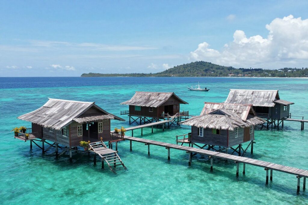 Traditional wooden stilt houses over water at Mabul Island with clear turquoise sea